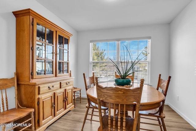 dining area with light wood-type flooring and baseboards