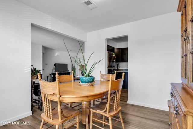 dining space with baseboards, visible vents, and wood finished floors