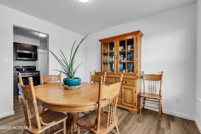 dining space featuring baseboards and light wood finished floors