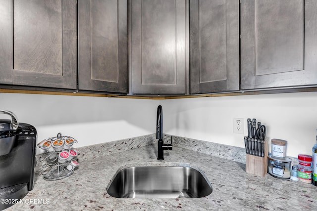 room details with light stone counters, a sink, and dark brown cabinets