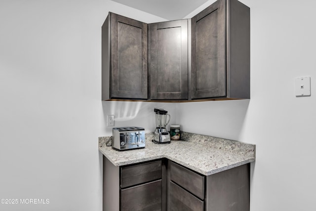 kitchen with light stone countertops and dark brown cabinetry