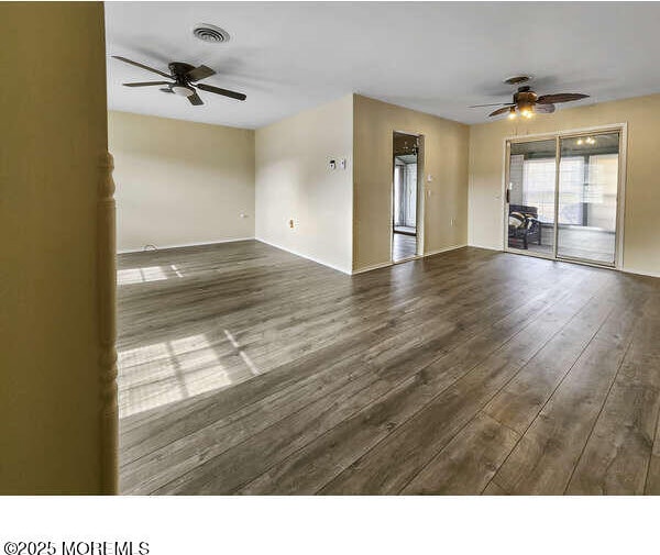 unfurnished room with visible vents, a ceiling fan, and wood finished floors