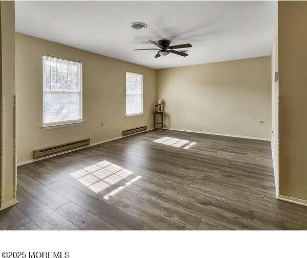 unfurnished room featuring a ceiling fan, a baseboard radiator, visible vents, and wood finished floors