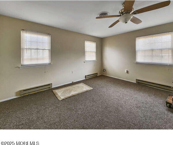 unfurnished room with carpet floors, a baseboard radiator, and baseboards