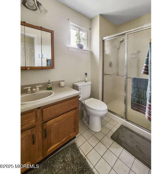 bathroom with toilet, tile patterned floors, a shower stall, and vanity