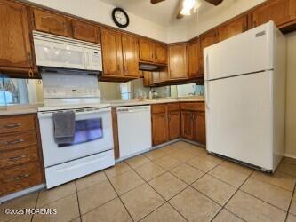 kitchen featuring light tile patterned floors, light countertops, white appliances, and brown cabinets