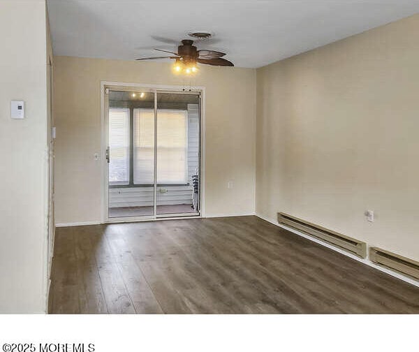 unfurnished room with ceiling fan, baseboard heating, and wood finished floors