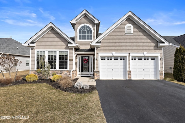 traditional home featuring stone siding, driveway, and an attached garage