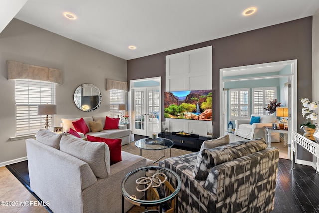 living area featuring plenty of natural light, baseboards, dark wood-style flooring, and french doors