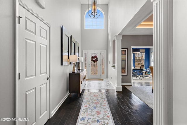 entrance foyer with ornate columns, baseboards, and dark wood finished floors