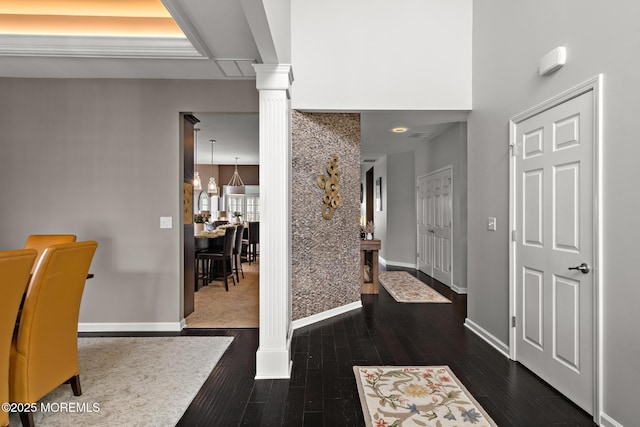 foyer with dark wood-style floors, baseboards, and ornate columns