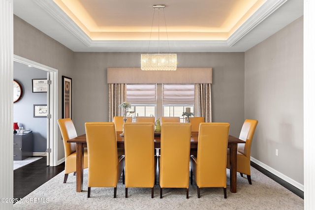 dining room featuring baseboards, a tray ceiling, and wood finished floors
