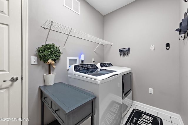clothes washing area with visible vents, washer and dryer, laundry area, baseboards, and tile patterned floors