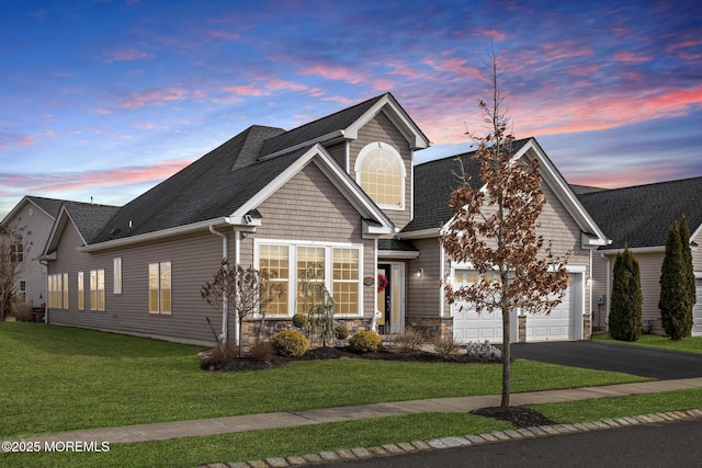 view of front of house featuring a garage, stone siding, aphalt driveway, roof with shingles, and a front yard