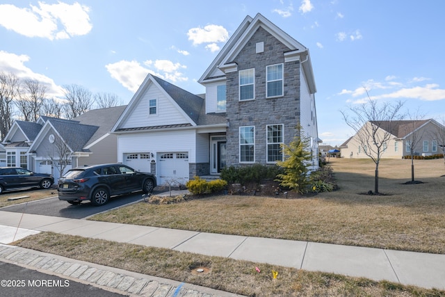 traditional home with driveway, stone siding, an attached garage, and a front lawn