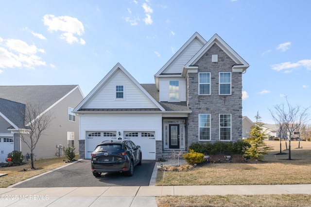 craftsman-style home with aphalt driveway, a front yard, a standing seam roof, metal roof, and stone siding