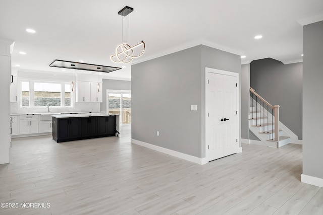 unfurnished living room featuring recessed lighting, crown molding, light wood finished floors, baseboards, and stairs