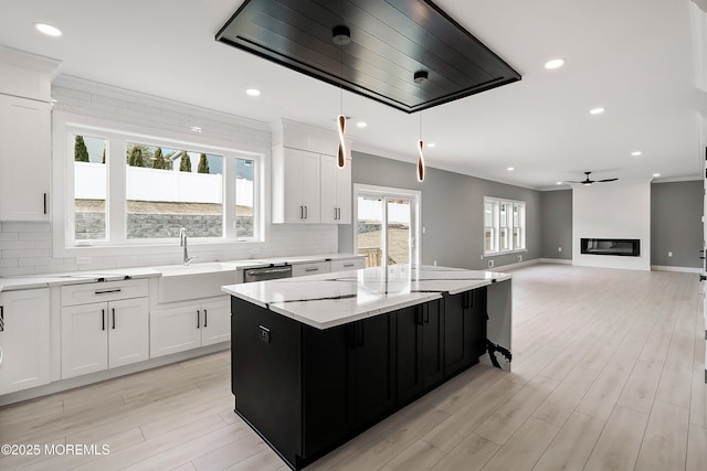 kitchen featuring a kitchen island, a fireplace, a sink, crown molding, and tasteful backsplash