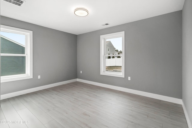 unfurnished room featuring wood finished floors, baseboards, and visible vents