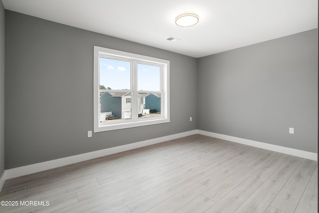 unfurnished room featuring visible vents, baseboards, and light wood-type flooring