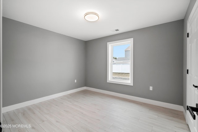 unfurnished room with light wood-type flooring, visible vents, and baseboards