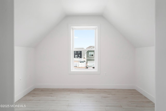 bonus room with baseboards, light wood-style floors, and vaulted ceiling