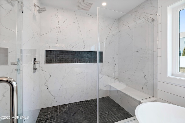 full bathroom featuring a soaking tub and a marble finish shower