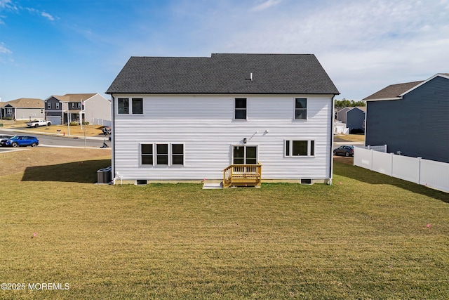 rear view of property featuring a residential view, a lawn, a shingled roof, and fence