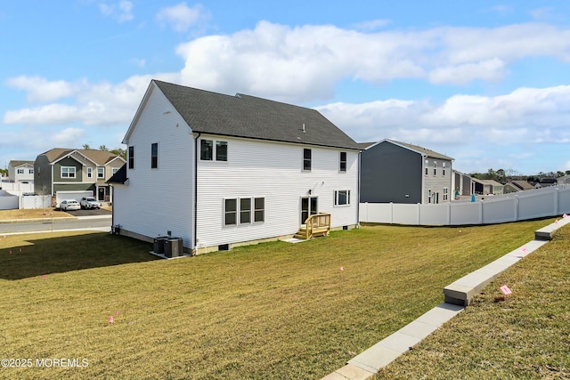 back of house featuring a lawn, fence, cooling unit, a residential view, and a shingled roof