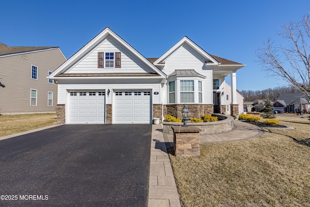 view of front of house featuring metal roof, driveway, a standing seam roof, and stone siding