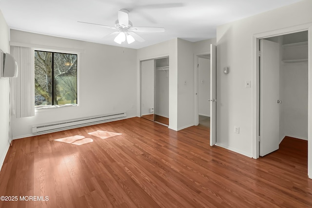 unfurnished bedroom with wood finished floors, a closet, a baseboard radiator, baseboards, and ceiling fan