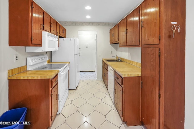 kitchen featuring white appliances, brown cabinetry, light countertops, and a sink