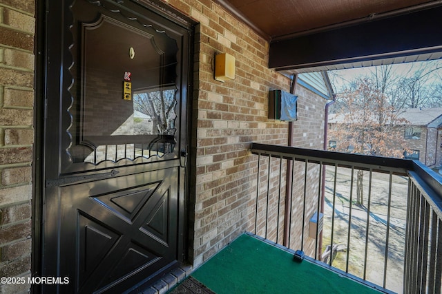 entrance to property featuring brick siding and a balcony