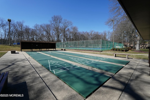 view of community featuring shuffleboard, a tennis court, and fence