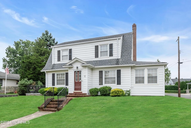 colonial inspired home with a front lawn, roof with shingles, and a chimney