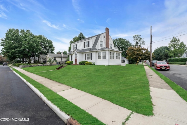 view of front of house with a shingled roof, a front yard, and a gambrel roof