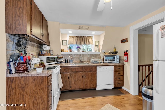 kitchen featuring light wood-type flooring, white appliances, decorative backsplash, and a sink