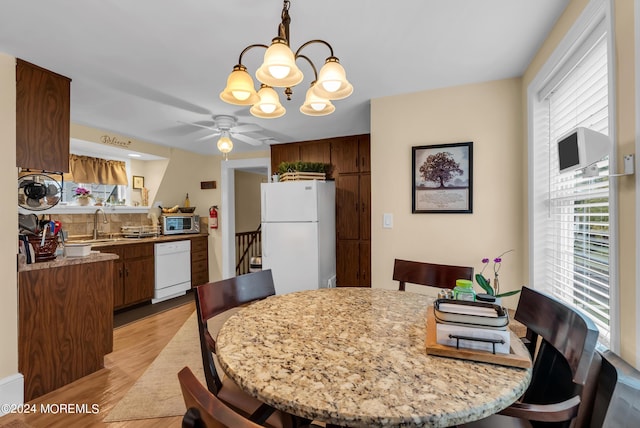 dining area with ceiling fan with notable chandelier and light wood-style flooring