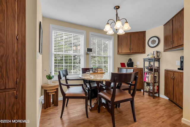 dining room featuring a notable chandelier, baseboards, and light wood-style floors