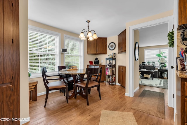 dining space with light wood finished floors, baseboards, and a notable chandelier