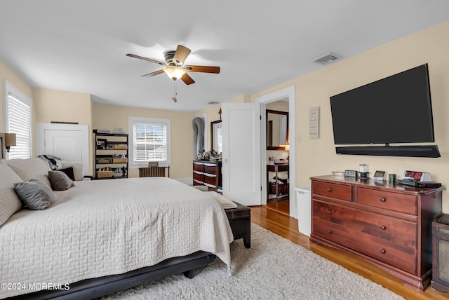 bedroom with wood finished floors, visible vents, and a ceiling fan