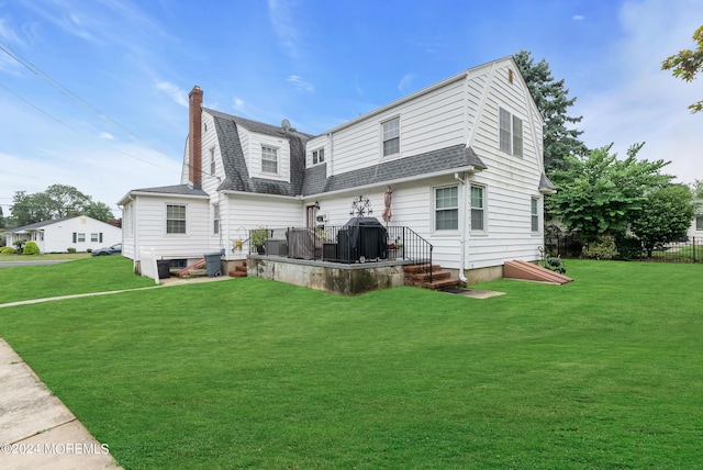 rear view of property with a shingled roof, a lawn, a chimney, and a gambrel roof