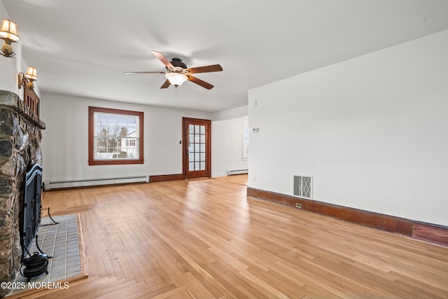 unfurnished living room featuring visible vents, baseboard heating, a baseboard heating unit, a fireplace with flush hearth, and a ceiling fan