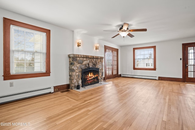 unfurnished living room featuring a fireplace, baseboard heating, a baseboard heating unit, ceiling fan, and hardwood / wood-style floors