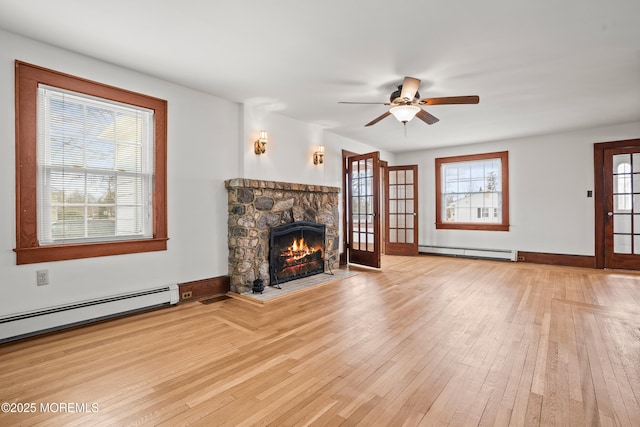 unfurnished living room featuring light wood finished floors, visible vents, baseboard heating, and a stone fireplace