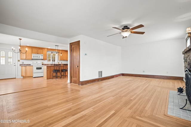 unfurnished living room featuring a fireplace with flush hearth, parquet flooring, baseboards, and ceiling fan with notable chandelier