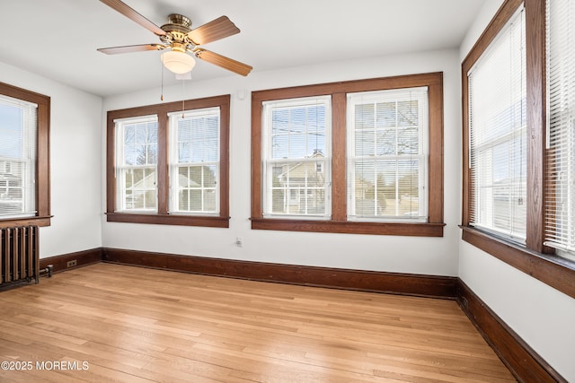 unfurnished sunroom with radiator heating unit and a ceiling fan