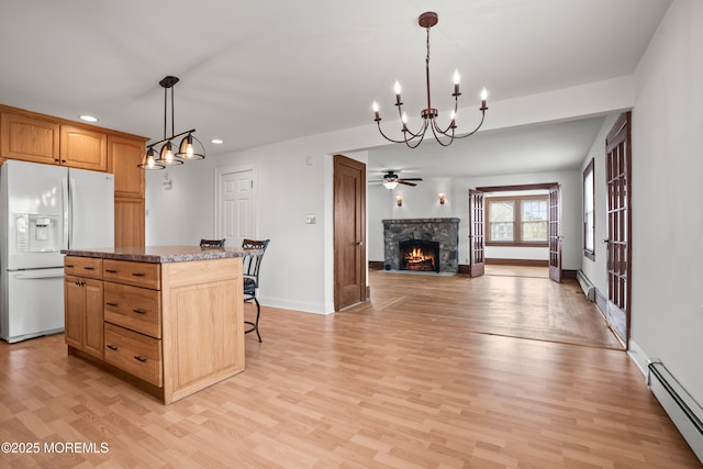 kitchen featuring open floor plan, white fridge with ice dispenser, light wood finished floors, and baseboard heating