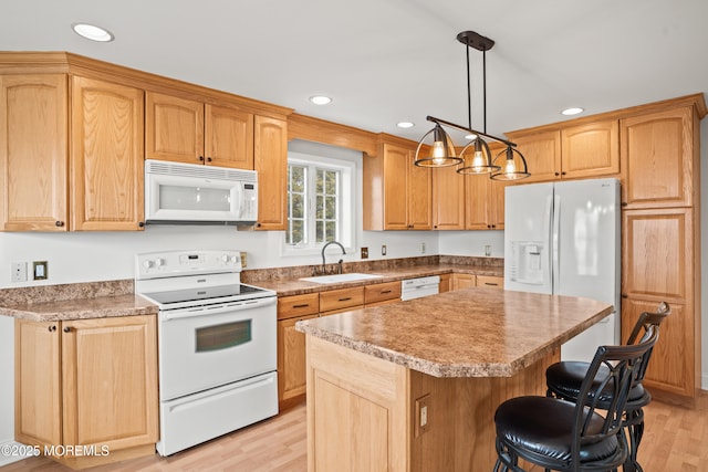 kitchen with white appliances, a kitchen island, a sink, a kitchen breakfast bar, and light wood-style floors