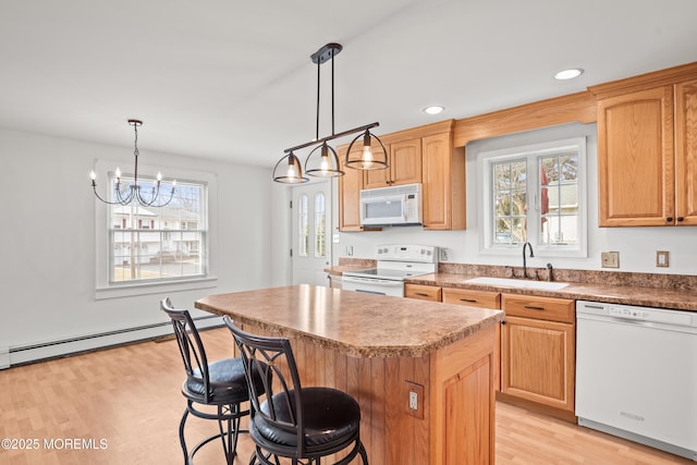 kitchen with white appliances, a kitchen island, plenty of natural light, and a sink